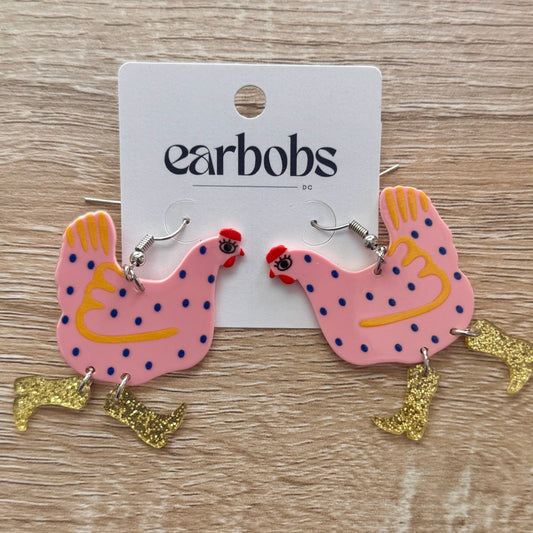 Pink chicken-shaped earrings with gold accents on a 'earbobs' card.